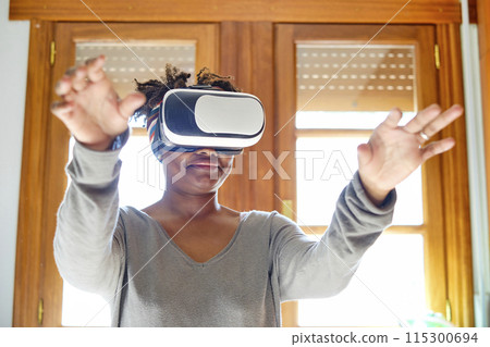 Young black woman testing a virual reality device. 115300694