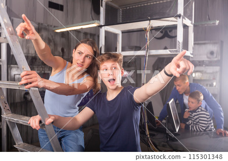 Young woman and a teenage boy saw the key to solving the puzzle in the quest room Young woman and a teenage boy saw the key to solving the puzzle in the quest room 115301348