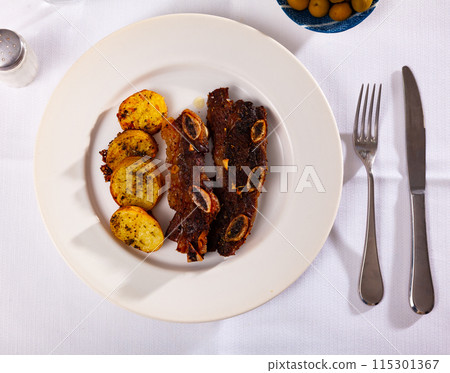 Spanish cuisine churrasco de ternera, spare ribs with potatoes on white ceramic plate Spanish cuisine churrasco de ternera, spare ribs with potatoes on white ceramic plate 115301367
