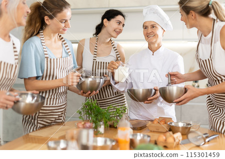 Elderly woman chef with bowl in hands tells women at culinary courses about traditions of cuisine 115301459