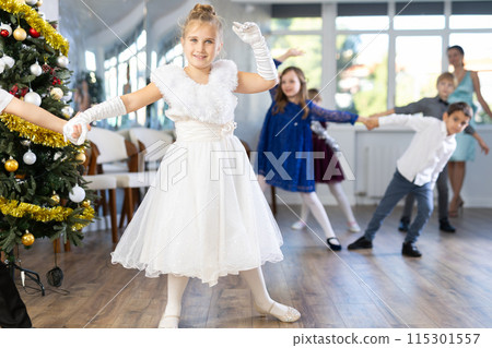 Little children practicing waltz dance in school-hall decorated with Christmas-tree 115301557