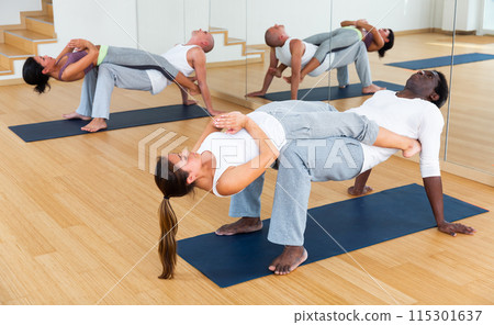 Women and men performing paired yoga exercises during group training Women and men performing paired yoga exercises during group training 115301637