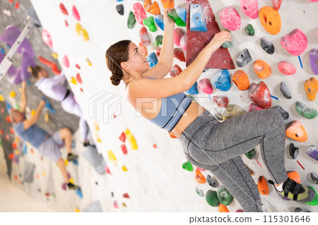 Young woman practicing rock climbing on climbing wall 115301646