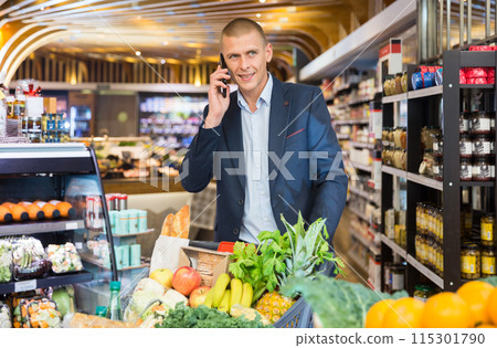 Man talking on phone in grocery supermarket Man talking on phone in grocery supermarket 115301790