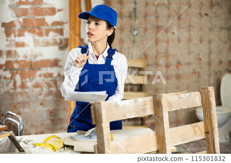 Positive female civil engineer taking notes while checking indoor construction site, satisfied with progress of work Positive female civil engineer taking notes while checking indoor construction site, satisfied with progress of work 115301832