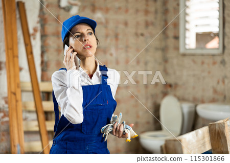 Female contractor talking on phone at construction site indoors 115301866