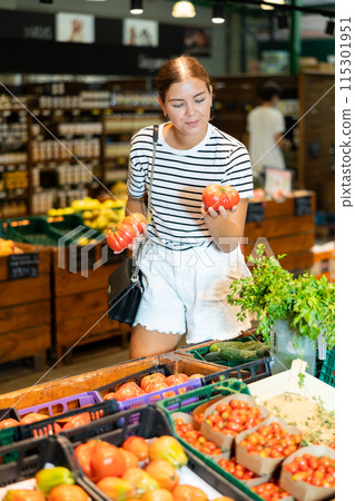 Young woman choosing tomatoes in grocery store 115301951