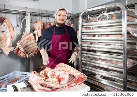 Male butcher shop butcher shows raw chopped carcasses and ribs Male butcher shop butcher shows raw chopped carcasses and ribs 115302006