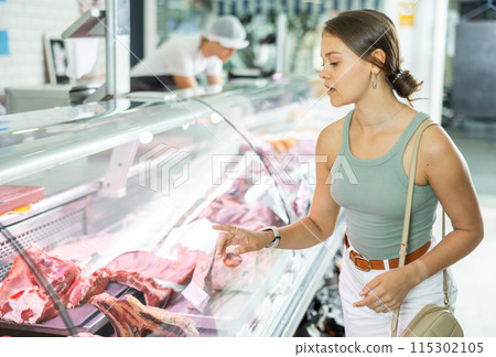 Young woman purchaser buying meat in butcher shop Young woman purchaser buying meat in butcher shop 115302105