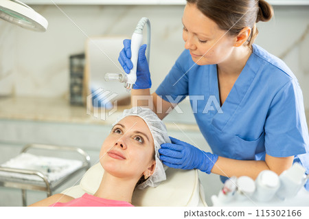 Beautiful female doctor making facial gas-liquid oxygen water epidermal peeling using professional equipment use macromolecule atomizing pen for young girl at spa salon. Skin care concept. Beauty 115302166