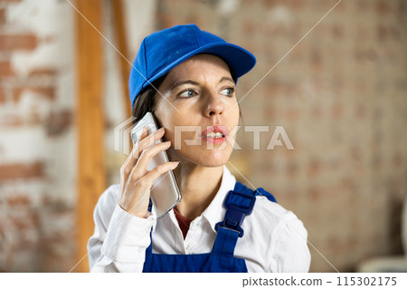 Female contractor talking on phone at construction site indoors Female contractor talking on phone at construction site indoors 115302175