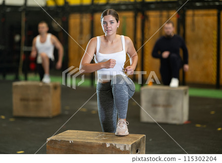 Young woman doing box step-ups in intensive group training 115302204