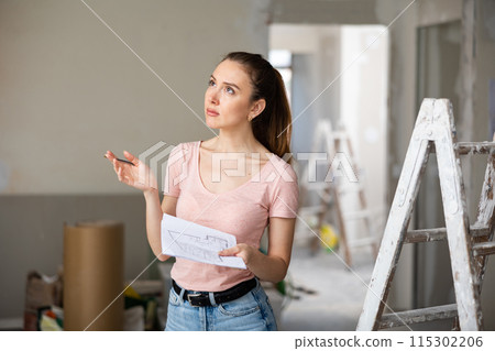Woman checking plan of house being renovated Woman checking plan of house being renovated 115302206