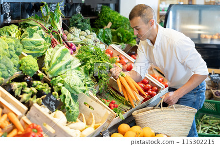 In vegetable department of bio supermarket, male customer took bunch of carrots from window 115302215