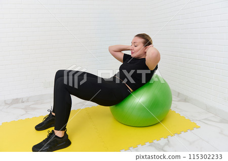 Young female athlete working out with stability ball at home studio for fitness 115302233