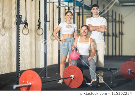 Two young women and guy posing in gym 115302234