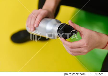 Young female athlete preparing water bottle during home workout with gym equipment Young female athlete preparing water bottle during home workout with gym equipment 115302245