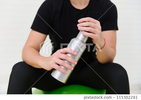 Young sporty woman working out at home with gym equipment and water bottle Young sporty woman working out at home with gym equipment and water bottle 115302281