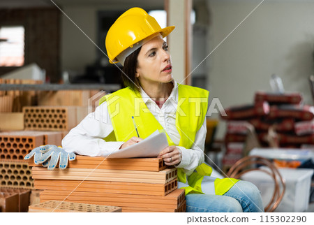 Female civil engineer making notes while controlling workflow at construction site 115302290