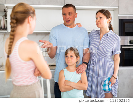 Girl with hair in braids stands in front of parents and listens to instructions about bad behavior 115302335