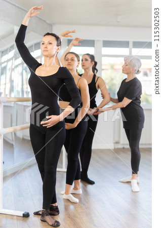 Elderly woman teacher corrects female dancers Elderly woman teacher corrects female dancers 115302503