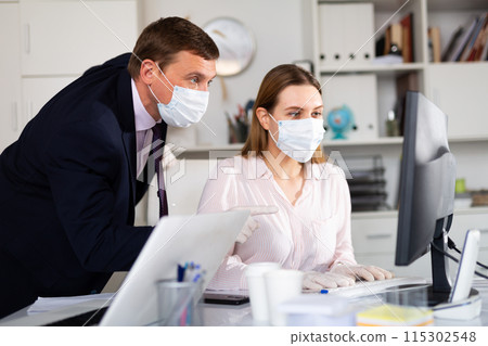 Entrepreneur in medical mask working with female coworker in office Entrepreneur in medical mask working with female coworker in office 115302548