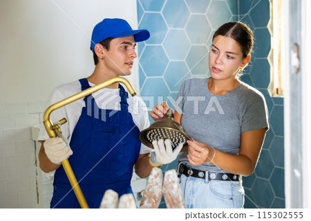 Woman asking for help from plumber in assembling new shower during renovation 115302555