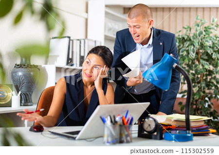 Frustrated female entrepreneur sitting at office desk with angry partner 115302559
