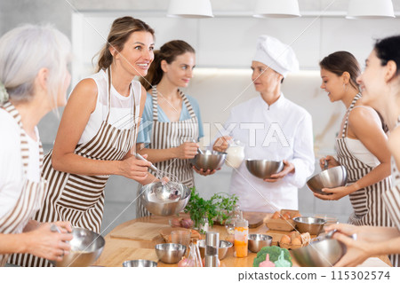 Young woman holding bowl and talking to other members Young woman holding bowl and talking to other members 115302574