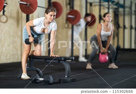 Young woman training with dumbbells on bench Young woman training with dumbbells on bench 115302688