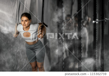 Girl trains on gymnastic rings in modern crossfit gym 115302739