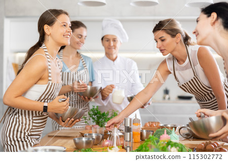 Young woman holding bowl and talking to other members Young woman holding bowl and talking to other members 115302772