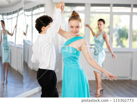 Couple of teenage dancers rehearsing ballroom dance with female teacher 115302773