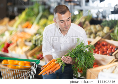 Young man purchaser buying organic carrot in grocery store Young man purchaser buying organic carrot in grocery store 115302816