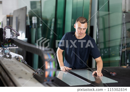 Glass workshop - man marks glass for cutting with glass cutter Glass workshop - man marks glass for cutting with glass cutter 115302834