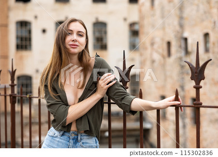 Woman in unbuttoned blouse posing near fence 115302836