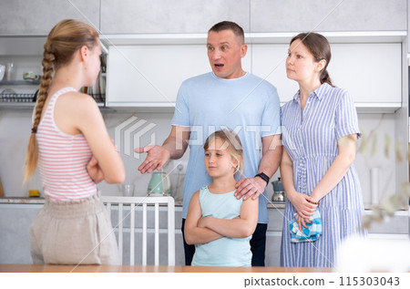 Girl with hair in braids stands in front of parents and listens to instructions about bad behavior Girl with hair in braids stands in front of parents and listens to instructions about bad behavior 115303043