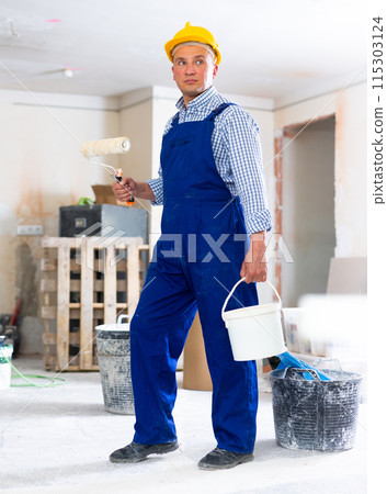 Man painter working in apartment, carrying bucket and roller Man painter working in apartment, carrying bucket and roller 115303124
