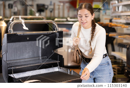 In store, girl inspects mobile grill, buys barbecue device 115303140