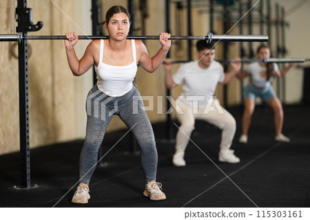 Young woman training with barbell in gym 115303161