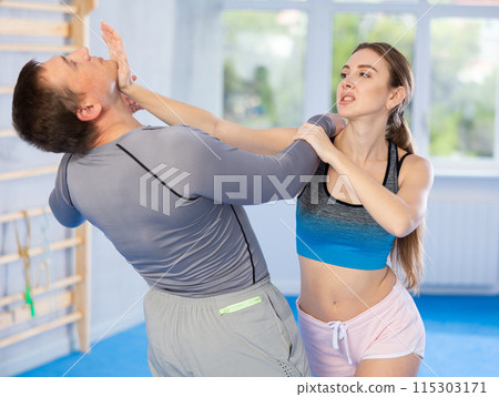 Young girl practicing self-defense techniques in pair with middle-aged man 115303171
