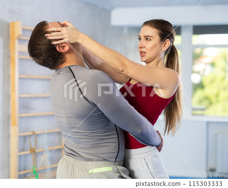 Young girl practicing self-defense techniques in pair with middle-aged man 115303333