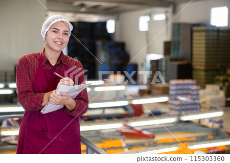 Young female supervisor with papers inspecting mandarins sorting workshop 115303360