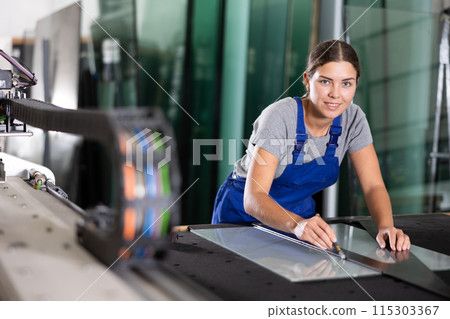Female worker cutting sheet of glass with manual glass cutter 115303367