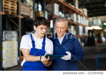 Guy check papers invoices together with mature employee and revise availability of goods in stock Guy check papers invoices together with mature employee and revise availability of goods in stock 115303492