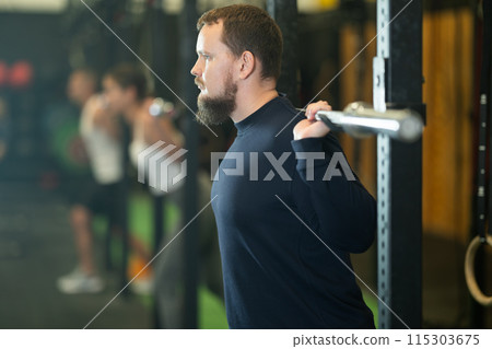 Young bearded man exercising with barbell during intense training 115303675