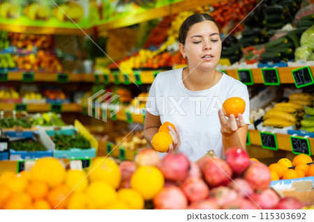 Happy young woman shopping and choosing oranges at supermarket 115303692