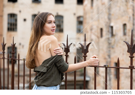Outdoor fashion - beautiful blonde woman posing near wrought iron fence 115303705