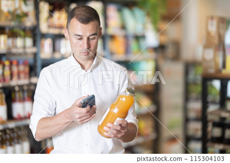 Man in supermarket scan QR code on bottle of drink 115304103