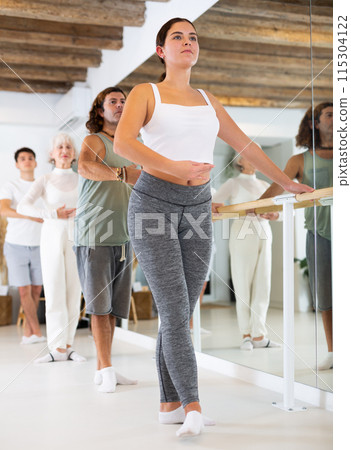 Young woman doing ballet at barre 115304122